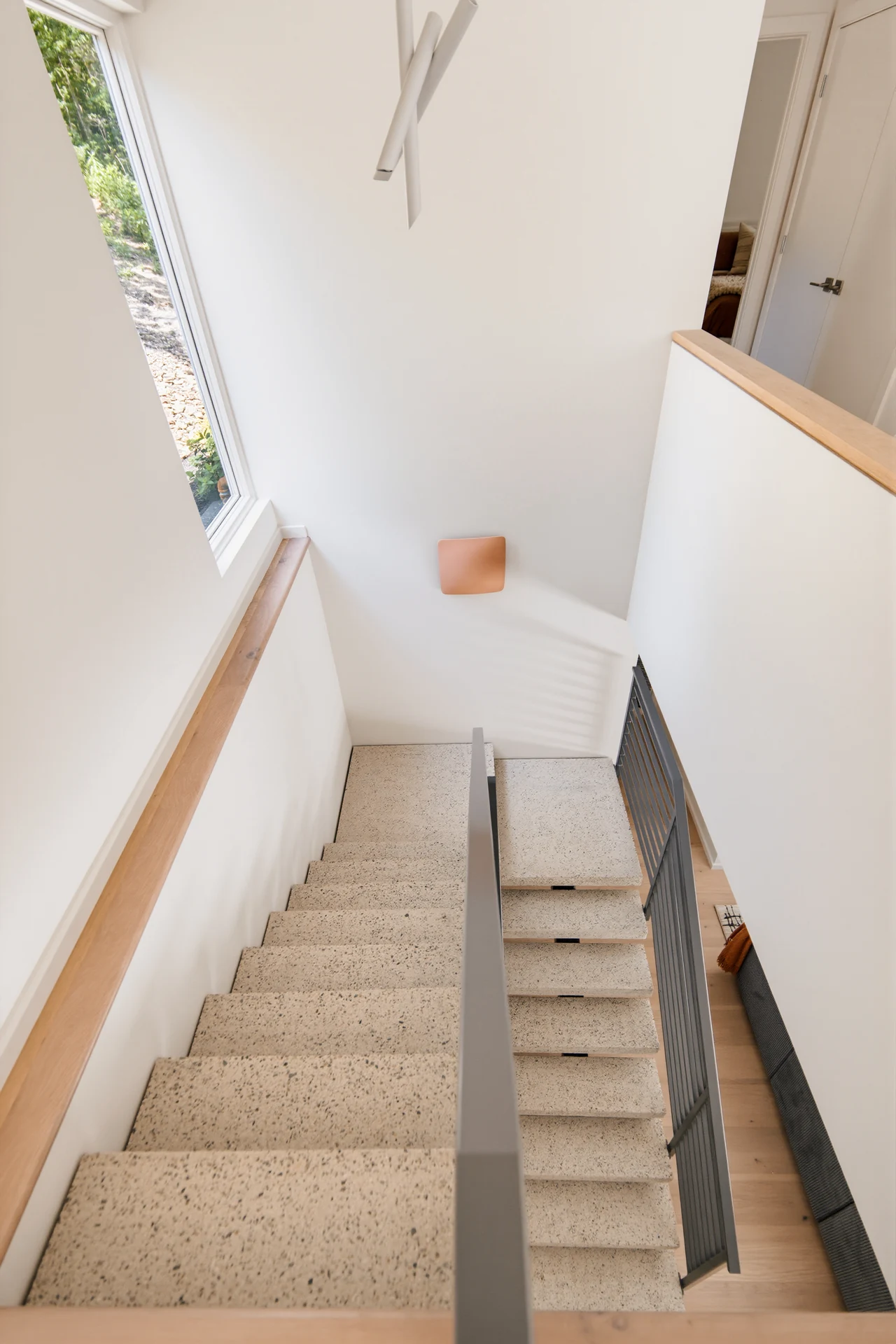 Stairway beneath tall windows and a wood ceiling beam