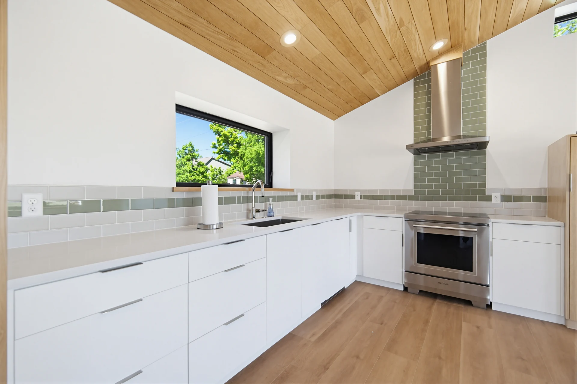 Kitchen cabinetry and range with a green tile accent