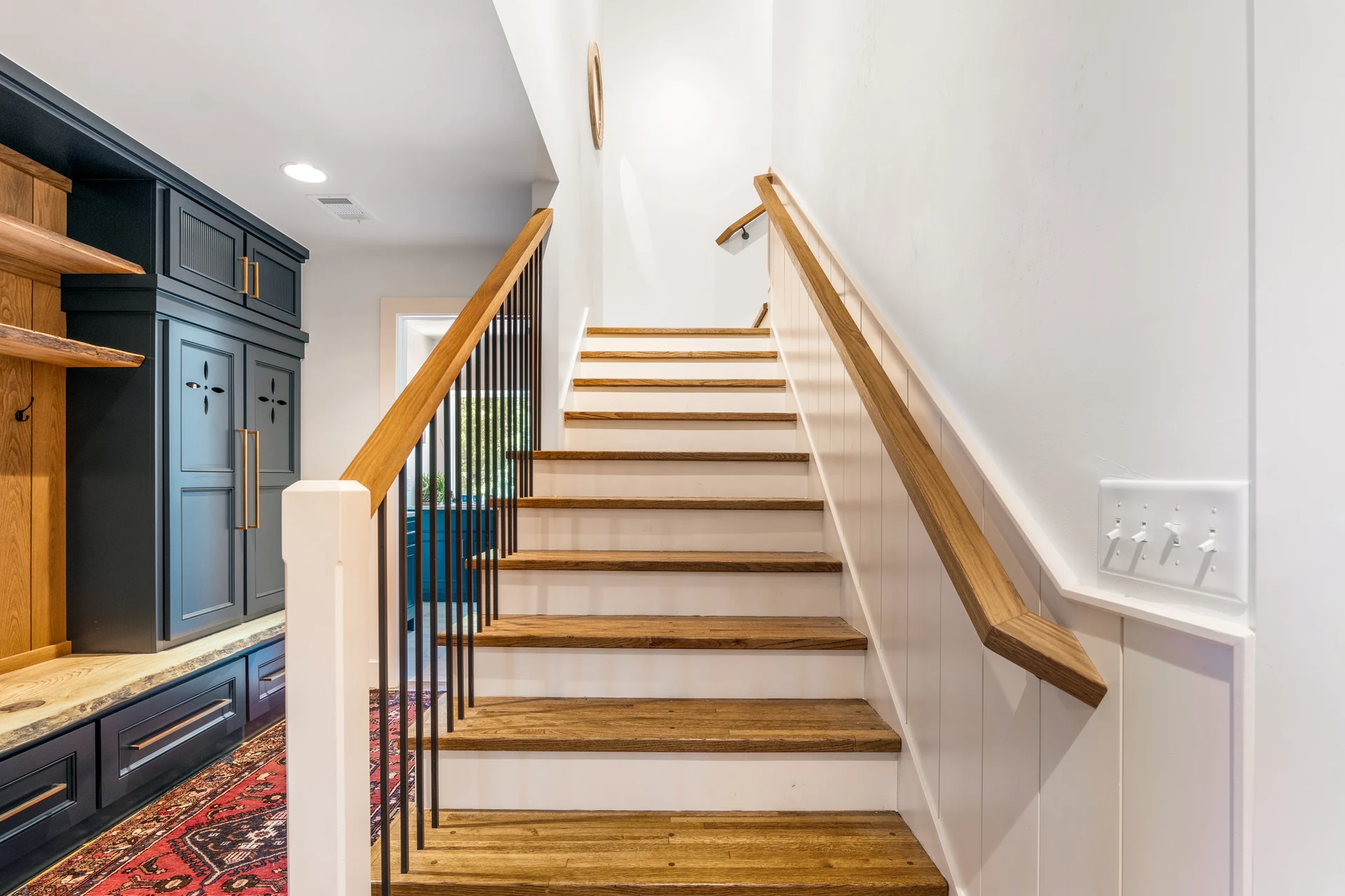 Wood stair treads and handrail beside the entry built-ins