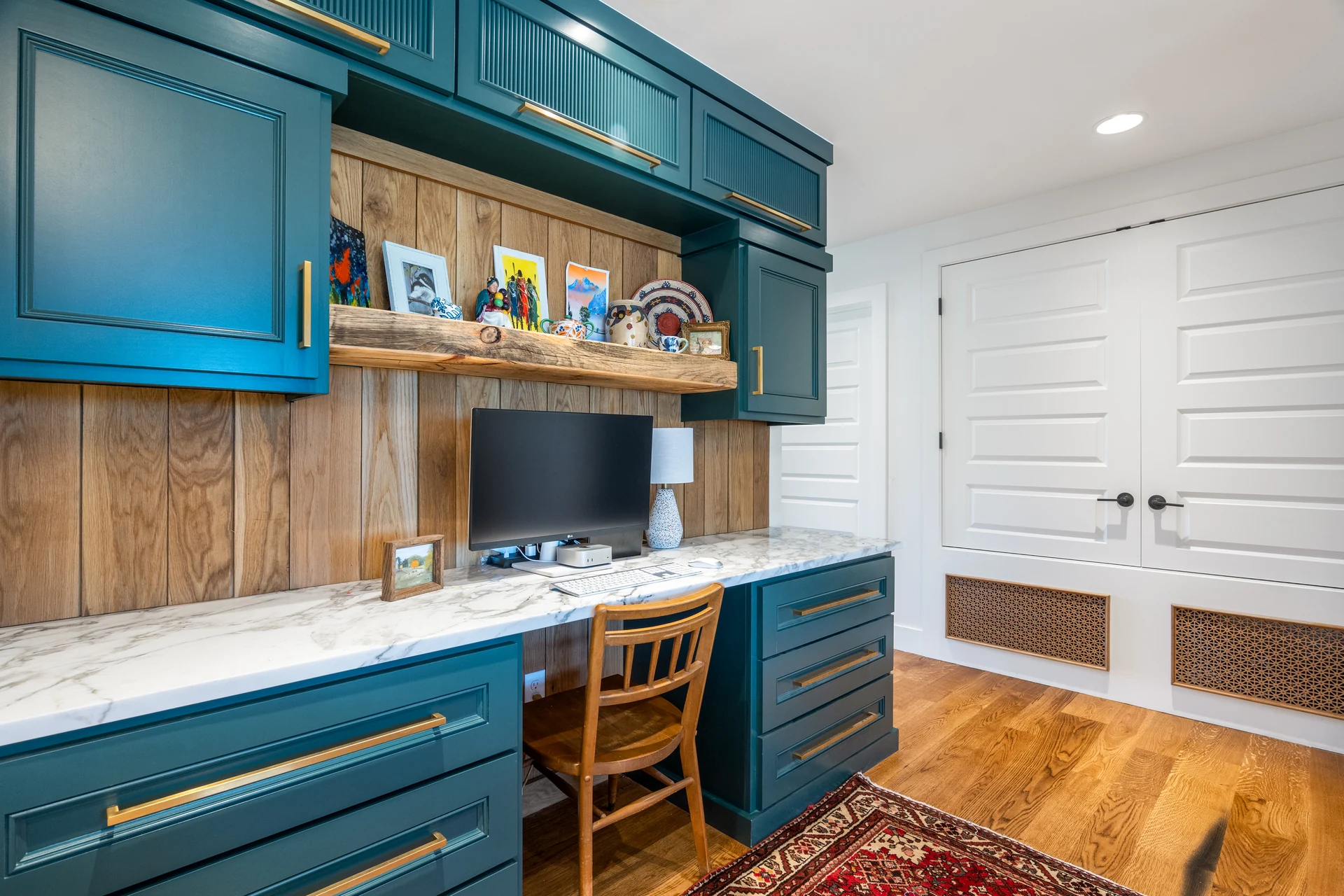 Built-in desk with open shelving and blue-green cabinetry