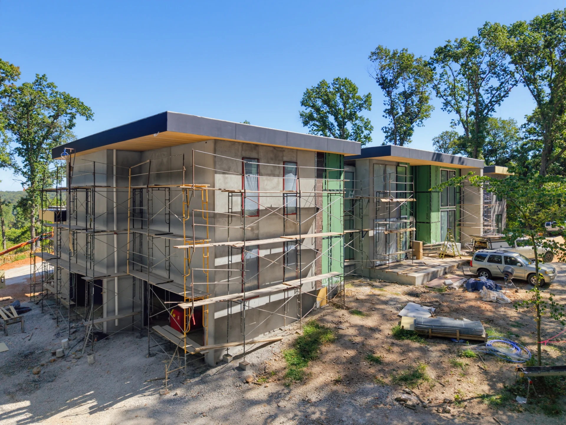 Exterior construction and scaffolding along a glazed building wing